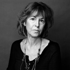 a black and white photo of a woman with necklaces on her neck looking at the camera