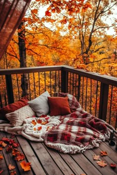 an outdoor deck with fall leaves and blankets on it