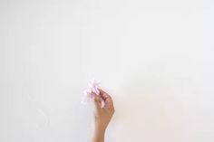 a person holding something in their hand against a white wall with pink flowers on it