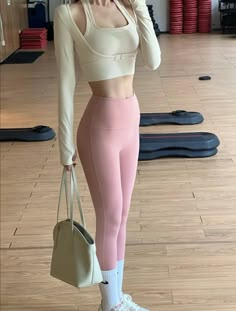 a woman in pink leggings and sports bra top taking a selfie with her cell phone