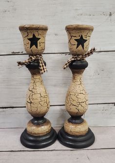 two wooden candlesticks decorated with black stars and burlock tied to them