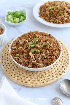 two bowls filled with rice on top of a table next to silverware and spoons