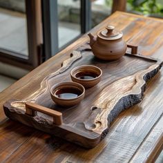 two bowls on a wooden tray with tea in them