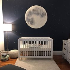 a baby's room with a white crib and stars in the sky on the wall