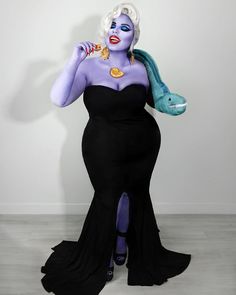 a woman in a black dress with purple hair and blue makeup is holding a fish