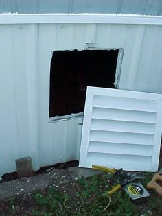 an open window in the side of a white building next to tools and other items