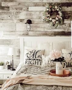 a white bed topped with lots of pillows next to a wall mounted clock and wreath