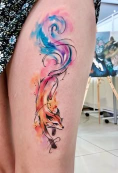 a woman's thigh with watercolor tattoos on her legs and an animal design