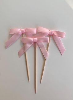 three wooden sticks with pink bows on them, tied together and ready to be used as toothpicks