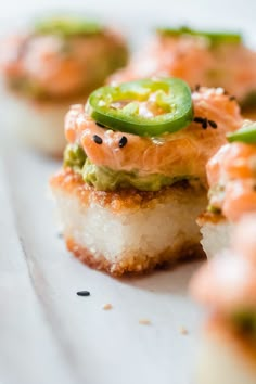 small appetizers with various toppings on them sitting on a white tablecloth