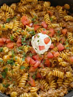 a skillet filled with pasta and meat covered in sauce, sour cream and garnish