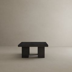 a small black table sitting on top of a white floor in front of a wall