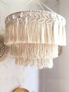 a white chandelier hanging from the ceiling next to a potted plant and wicker basket