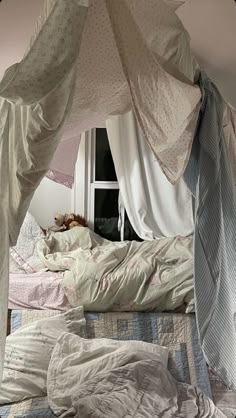 an unmade bed with white sheets and curtains