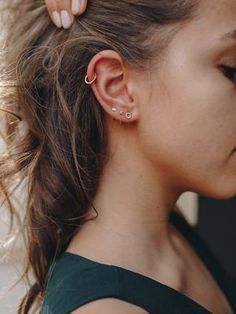 a woman with her hair in a ponytail and ear piercings is looking at the camera