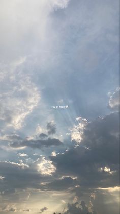 the sky is filled with clouds and sun beams in it's center, as seen from an airplane