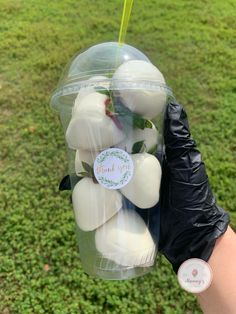 a person holding up a plastic container filled with white soap on top of a lush green field