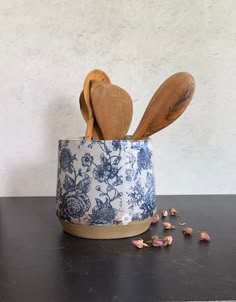 two wooden utensils in a blue and white flowered cup with spoons