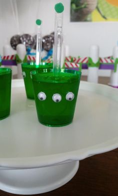 two green cups with toothbrushes in them on a white plate and decorated table