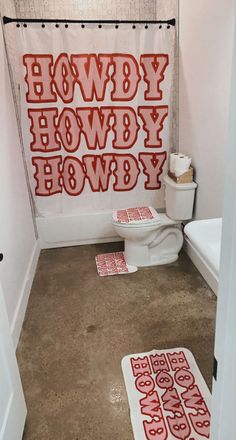 a bathroom with red letters on the shower curtain and rugs in front of it