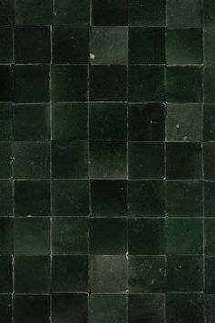 a black and green tiled wall with small squares on it's sides, as well as the floor