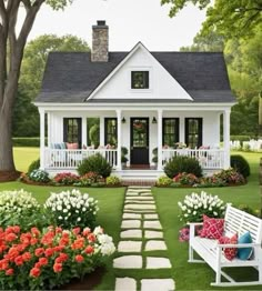 a white house with flowers in the front yard and steps leading up to it's porch