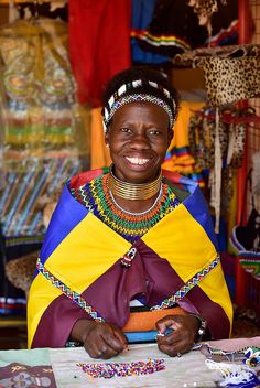 a woman sitting at a table with beads on her neck