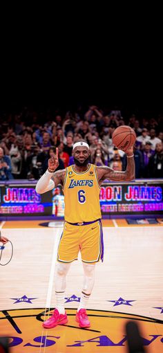 a man holding a basketball while standing on top of a basketball court in front of a crowd