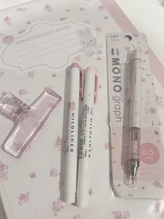 two pens are sitting next to each other on a table with pink and white flowers