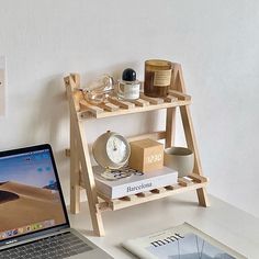 an open laptop computer sitting on top of a desk next to a shelf with books