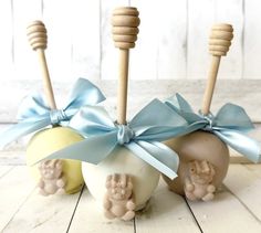 three apples with blue bows on them sitting in front of two wooden sticks and one has an apple shaped like a baby's hand