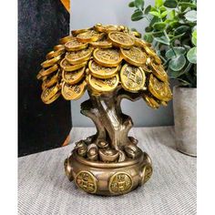 a small tree made out of gold coins on a table next to a potted plant