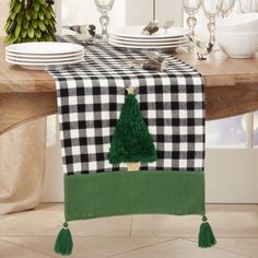 the table is set with black and white checkered linens, green tassels, and a small christmas tree