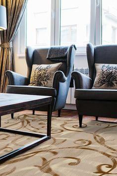 two chairs and a coffee table in front of a window with curtains on the windowsill