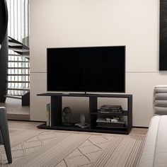 a flat screen tv sitting on top of a wooden stand in a living room next to a stair case