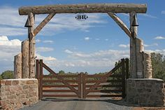 a wooden gate is open on a dirt road