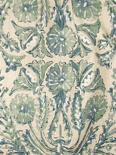 an old, green and white fabric with flowers on the bottom half is shown in close up