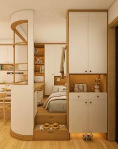 a bedroom with wooden flooring and white cupboards next to a bed in a small room