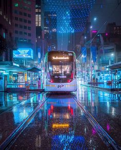 a public transit bus on a city street at night with lights reflecting off the wet pavement