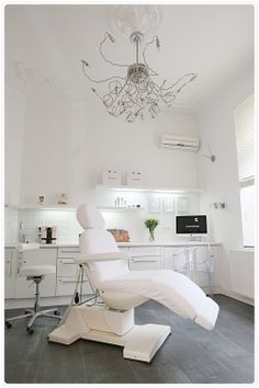 a modern dental room with white furniture and chandelier