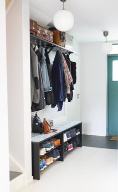 an entryway with coat racks and shoes on the floor, next to a blue door