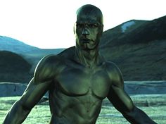 a man standing in the middle of a field with no shirt on