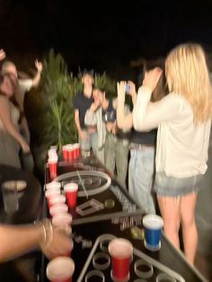 a group of people standing around a table with cups on it and drinks in front of them