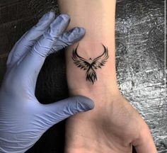 a person with gloves on their hands is holding up a small tattoo that looks like an eagle