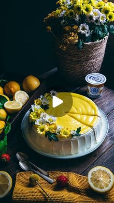 a cake sitting on top of a wooden table next to lemons and strawberries