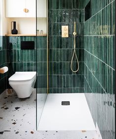 a green tiled bathroom with a toilet and shower