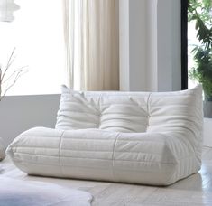 a white couch sitting on top of a hard wood floor next to a vase filled with flowers