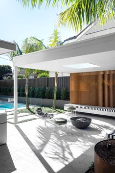 an outdoor living area with chairs, tables and a pool in the back ground is surrounded by palm trees