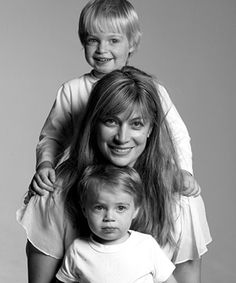 a woman and two children are posing for a black and white photo in front of a gray background