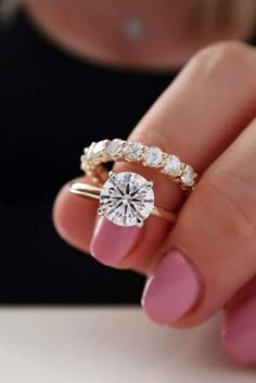 a woman's hand holding a diamond ring with two diamonds on it, and the middle